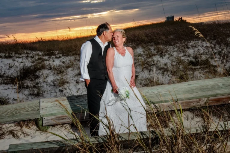 Bride and groom standing in a beautiful sunset, kissing each other. Golf Shores Photography