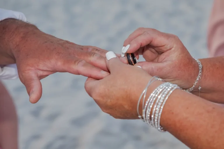 Photo of the bride putting the ring on the groom shot by Gulf Shores photographer.